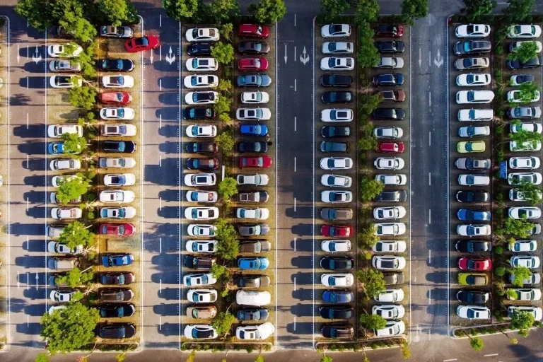 Aerial view of a parking lot filled with cars and lined with trees.