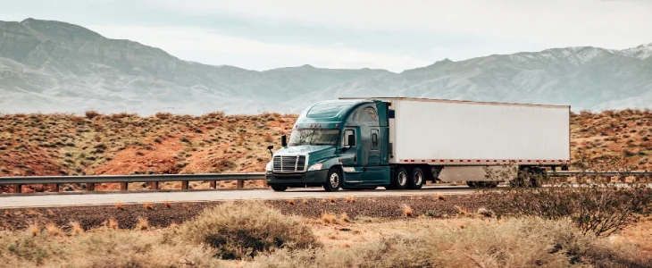 Commercial vehicle driving down a long highway in the desert